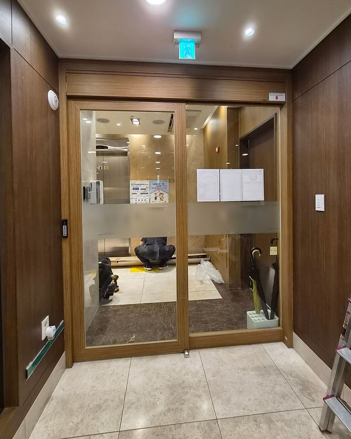 자동문 수리 — 건물 로비의 나무 테 슬라이딩 자동문